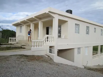a man standing on the steps of a white house at Villa Mambo in Patrana