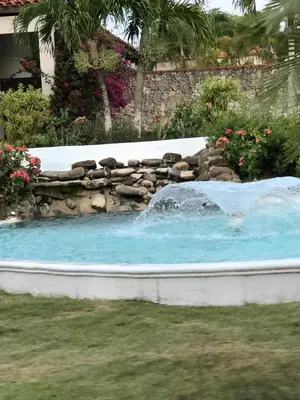 a swimming pool with a waterfall in a yard at Residencial Green Paradise at Metro Country Club Juan Dolio - 2 Bedroom with Balcony in Juan Dolio