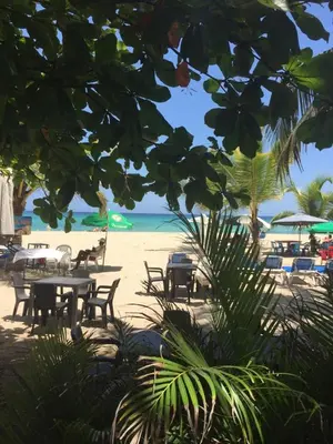 a beach with tables and chairs and the ocean at Residencial Green Paradise at Metro Country Club Juan Dolio - 2 Bedroom with Balcony in Juan Dolio