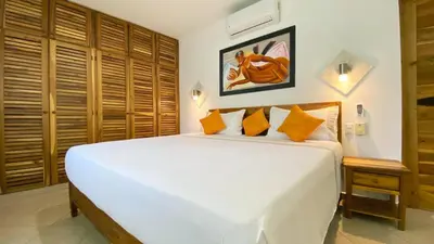 a bedroom with a large white bed with orange pillows at Albachiara Hotel - Las Terrenas in Las Terrenas