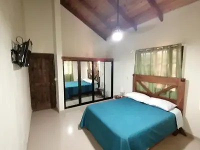 a bedroom with a blue bed and a mirror at Villa Laura Jarabacoa in Jarabacoa
