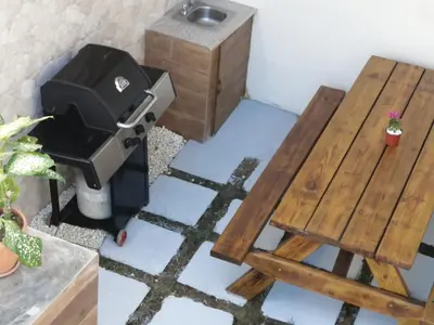 a room with a grill and a wooden table and bench at Villa Laura Jarabacoa in Jarabacoa
