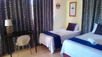 a room with two beds and a table and a desk at Casa D9 in Santo Domingo