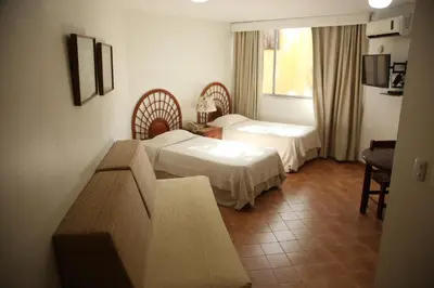 a hotel room with two beds and a couch at Aparta Hotel Plaza del Sol in Santo Domingo