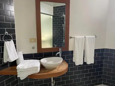 a bathroom with a sink and a mirror and towels at Aparta Hotel Plaza del Sol in Santo Domingo