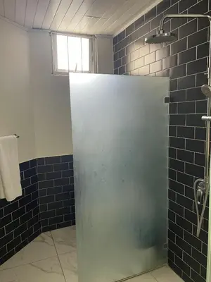 a bathroom with a shower with a glass door at Aparta Hotel Plaza del Sol in Santo Domingo