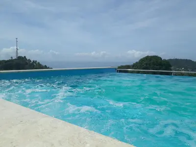 a swimming pool with a view of the ocean at Figaro Hotel Samana in Santa Bárbara de Samaná