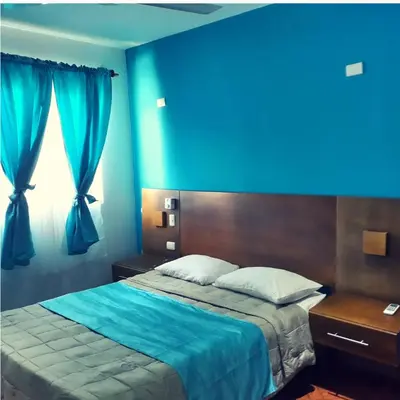 a bedroom with a bed with a blue wall at Figaro Hotel Samana in Santa Bárbara de Samaná