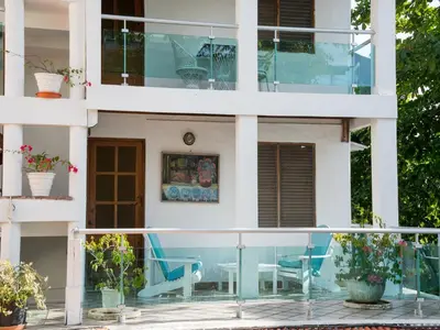 a house with a balcony with blue chairs at Hotel Neptuno Refugio in Boca Chica