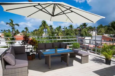 a patio with a table and chairs and an umbrella at Terraza Art Villa Dominicana in Punta Cana