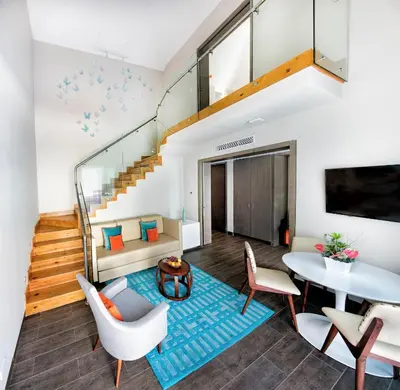 a living room with a staircase and a table and chairs at Nickelodeon Hotels & Resorts Punta Cana - Gourmet All Inclusive by Karisma in Punta Cana