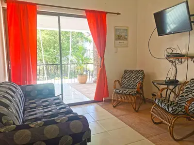 a living room with a couch and chairs and a sliding glass door at Perla de Sosua in Sosúa