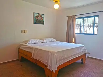 a bedroom with a bed in a room with a window at Perla de Sosua in Sosúa