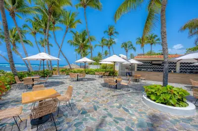 a patio with tables and chairs and palm trees at Coral Costa Caribe Beach Resort - All Inclusive in Juan Dolio
