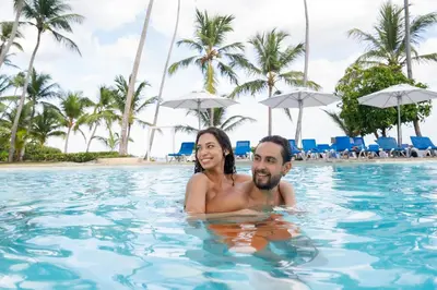 a man and woman swimming in the swimming pool at a resort at Coral Costa Caribe Beach Resort - All Inclusive in Juan Dolio