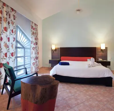 a bedroom with a bed and a chair and a table at VH - Gran Ventana Beach Resort in San Felipe de Puerto Plata