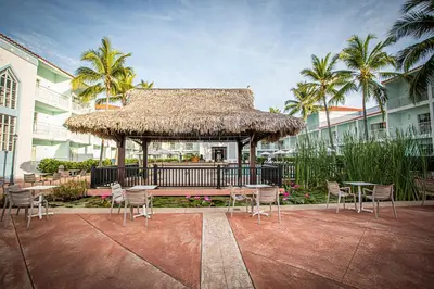 a gazebo with tables and chairs and palm trees at VH - Gran Ventana Beach Resort in San Felipe de Puerto Plata