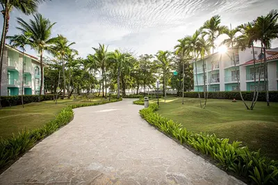 a walkway in a park with palm trees and buildings at VH - Gran Ventana Beach Resort in San Felipe de Puerto Plata