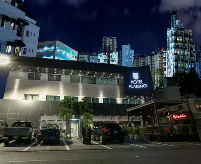 a building with cars parked in a parking lot at night at Hotel Aladino in Santo Domingo