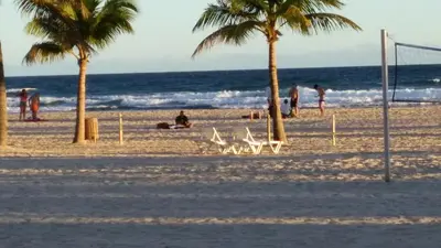 people on a beach with palm trees and the ocean at Juan Dolio Costa del Sol in Juan Dolio