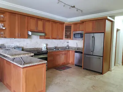 a kitchen with wooden cabinets and a stainless steel refrigerator at Luxury Oceanview Condo 2 BR/2.5 BA in Sosúa
