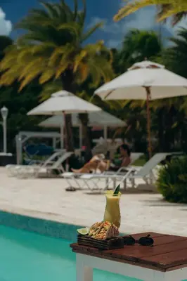 a table with a drink on it next to a pool at The Bannister Hotel & Yacht Club by Mint in Santa Bárbara de Samaná