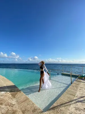 a woman in a bikini standing in the water next to the ocean at The Bannister Hotel & Yacht Club by Mint in Santa Bárbara de Samaná