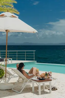 a woman sitting in a chair next to a pool at The Bannister Hotel & Yacht Club by Mint in Santa Bárbara de Samaná