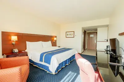 a hotel room with a bed and two chairs at Hodelpa Garden Court in Santiago de los Caballeros