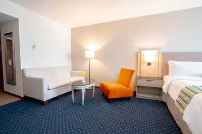 a hotel room with a bed and a chair at Hodelpa Garden Court in Santiago de los Caballeros