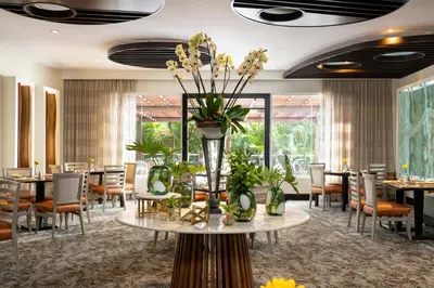 a dining room with tables and chairs and a vase with flowers at Hodelpa Garden Court in Santiago de los Caballeros