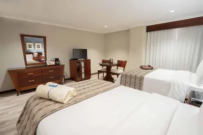 a hotel room with two beds and a mirror at Hodelpa Gran Almirante in Santiago de los Caballeros