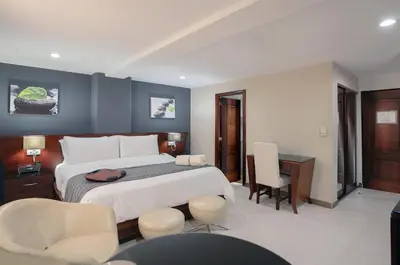 a bedroom with a bed and a desk and chairs at Hodelpa Gran Almirante in Santiago de los Caballeros
