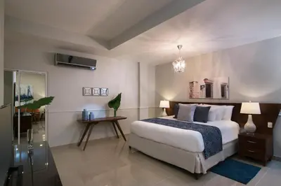 a bedroom with a large bed and a table at Hodelpa Caribe Colonial in Santo Domingo