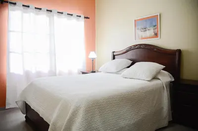 a bedroom with a bed with white sheets and a window at Hostal Bella Epoca in Santo Domingo