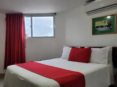 a bed in a room with a red window at Hotel Olimpo in La Romana