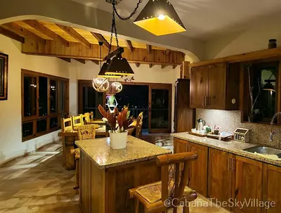 a kitchen with wooden cabinets and a island with a counter top at Villa The sky village in Jarabacoa