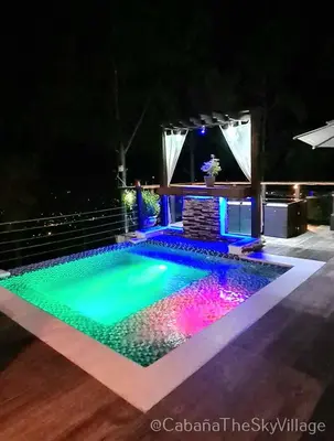 a swimming pool in a backyard at night at Villa The sky village in Jarabacoa