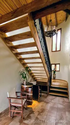 a living room with a staircase and a table and a chair at Villa The sky village in Jarabacoa