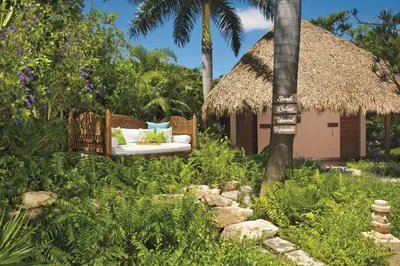 a garden with a couch and a hut at Zoetry Agua Punta Cana - All Inclusive in Punta Cana