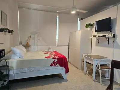 a bedroom with a bed and a desk and a tv at Apartamento Costa Azul en El Pueblito in San Felipe de Puerto Plata