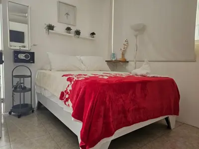 a bedroom with a bed with a red blanket on it at Apartamento Costa Azul en El Pueblito in San Felipe de Puerto Plata