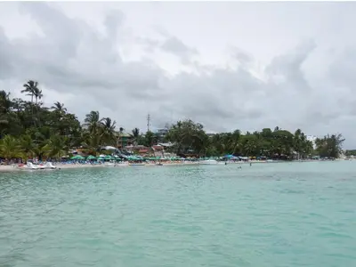 a beach with people and umbrellas in the water at Hotel Garant & Suites in Boca Chica