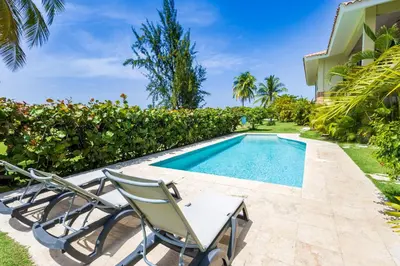 a swimming pool with two chairs next to a house at Private & Luxury Apartment Cocotal in Gated & Secured Community in Punta Cana