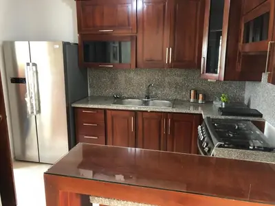 a kitchen with wooden cabinets and a stainless steel refrigerator at SFMverdana Rental in San Francisco de Macorís