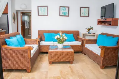 a living room with wicker furniture and blue pillows at Monserrat Residences in Las Terrenas