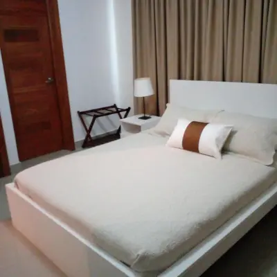 a bedroom with a white bed with a brown and white pillow at Cozy apartment in exclusive area Bella Vista in Santo Domingo