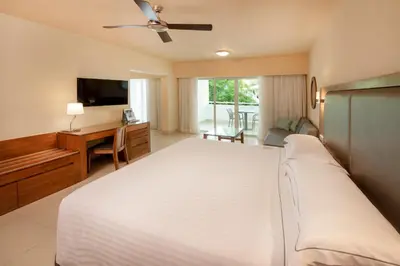 a bedroom with a large white bed and a desk at Occidental Punta Cana - All Inclusive in Punta Cana