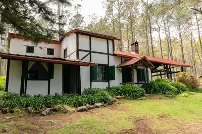 a white house with a green door and trees at Villa Pajon Eco Lodge in Constanza