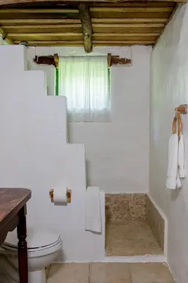 a white bathroom with a toilet and a window at Villa Pajon Eco Lodge in Constanza